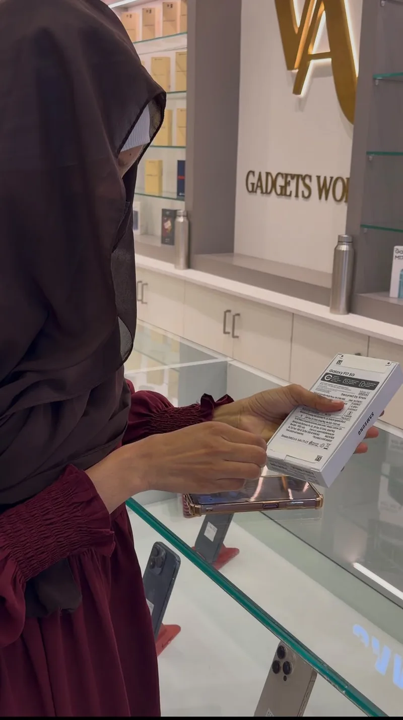 A customer at the VA Gadgets World counter reading the box of a new Samsung Galaxy F17 5G.